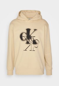 Felpa color beige chiaro con vestibilità ampia, dotata di una grafica nera con lettere stilizzate sul davanti e cappuccio con coulisse.