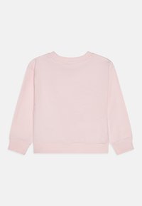 Vaaleanpunainen puuvillapaita, jossa on pyöreä kaula-aukko, pitkät hihat ja ribbaustyyliset hihansuut. Takapuoli on yksinkertainen, ja siinä on pehmeä pinta.