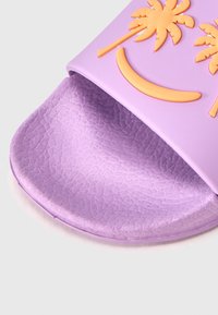 Lilla libisev sandaal, valmistatud siledast kummist, millel on reljeefsed oranžid palmipuud ja naeratuse kujutised. Tekstuuriga tallaosa haarduvuse ja mugavuse tagamiseks.