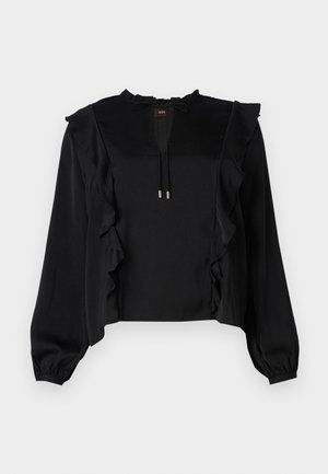 Zwarte blouse met lange mouwen en gerimpelde accenten langs de voorkant en schouders, voorzien van een strikdetail bij de hals en een gladde, zachte stofstructuur.