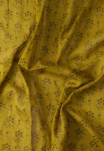 Κίτρινο ύφασμα με ελαφριά, ρέουσα υφή, που διαθέτει λουλουδένιο και φυλλώδες μοτίβο σε πιο σκοτεινές αποχρώσεις, δημιουργώντας ένα λεπτεπίλεπτο σχέδιο.
