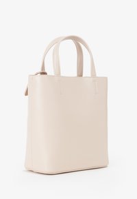 Piccola borsa in pelle beige con due manici corti e cuciture minimaliste su uno sfondo bianco.