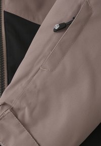 Ljust lila jacka i tyg med fiskbensmönster, med en svart accent och en dragkedjeficka på ärmen. Strukturerad yta.