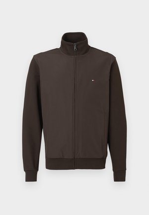 Brun full-zip jakke med ståkrage, sidelommer, ribbestrikkede mansjetter og nederkant, samt en liten rød, hvit og blå logo på brystet.