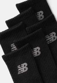 Calzini sportivi neri, texture a coste, con logo New Balance grigio. Sei paia impilati, con apertura a risvolto nella parte superiore.