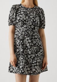 Černé šaty s bílými květinovými vzory růží a listů, krátké nafouknuté rukávy, kulatý výstřih a volný silueta.