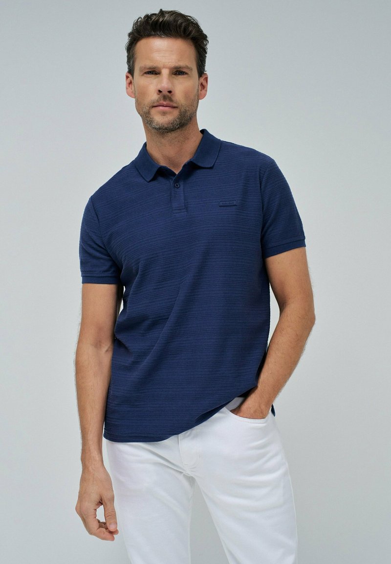 Camisa polo azul marino con un patrón de rayas texturadas, cuenta con un cuello clásico, una tapeta de dos botones y un pequeño logo en el pecho.
