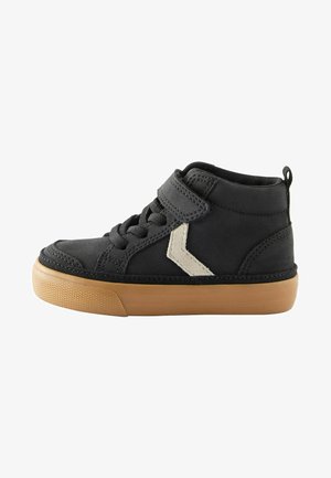 Scarpe nere alte in pelle. Presentano una fascia laterale bianca, una suola in gomma e una combinazione di lacci e un cinturino in Velcro per la chiusura.