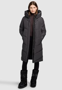 Palton lung căptușit negru cu glugă, fermoar frontal, buzunare laterale și design matlasat. Include, de asemenea, cizme izolate negre.