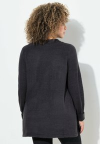 Maglione grigio scuro a maniche lunghe con vestibilità comoda, scollatura a girocollo e polsini a coste. Texture morbida con un orlo posteriore leggermente più lungo.