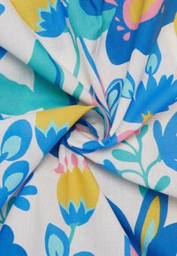 Bunte Baumwollstoffe mit einem floralen Muster in Blau, Gelb, Pink und Türkis auf einem weißen Hintergrund, der verschiedene Pflanzenformen und -texturen zeigt.