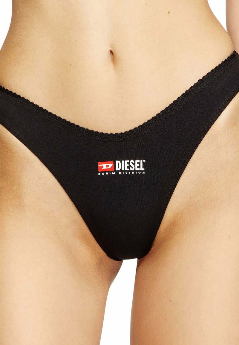Zwarte katoenen thong met een golvende tailleband, voorzien van een rood-wit Diesel Denim Division-logo aan de voorkant. Gladde textuur.