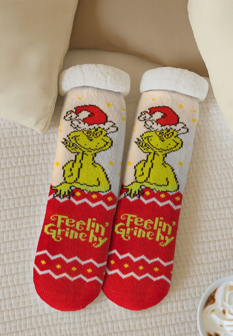 Calze pelose rosse e bianche con un Grinch verde che indossa un cappello da Babbo Natale rosso, con la scritta "Feelin' Grinchy" e motivi natalizi.