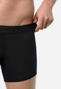 Boxer shorts neri con una texture liscia e un design aderente. La cintura elastica presenta un logo discreto. Nessun motivo o accento visibile.