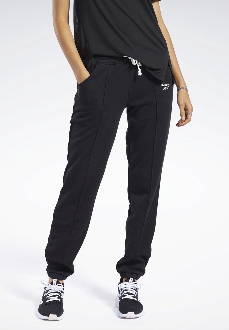Pantalones de chándal negros hechos de tela suave, con bolsillos laterales, puños elásticos y cintura con cordón. Logo mostrado en el muslo izquierdo.