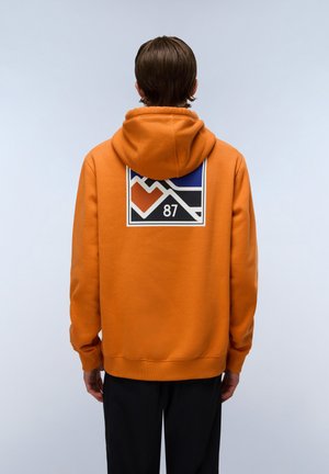 Orange hoodie with a large geometric design on the back, featuring blue, white, and red accents along with the number "87," soft texture.