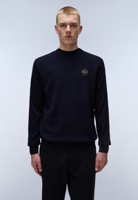 Marineblauwe ronde halstrui met een getextureerd bovenpaneel en ribgebreide manchetten, met een ronde logobadge op de borst. Effen stof door het hele kledingstuk.