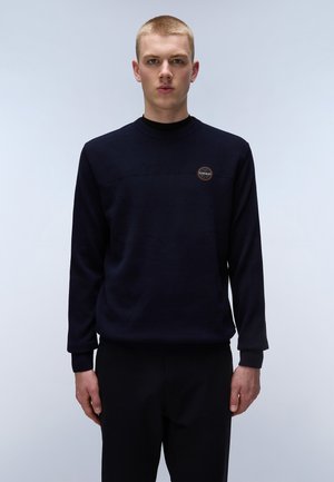 Marineblauwe ronde halstrui met een getextureerd bovenpaneel en ribgebreide manchetten, met een ronde logobadge op de borst. Effen stof door het hele kledingstuk.