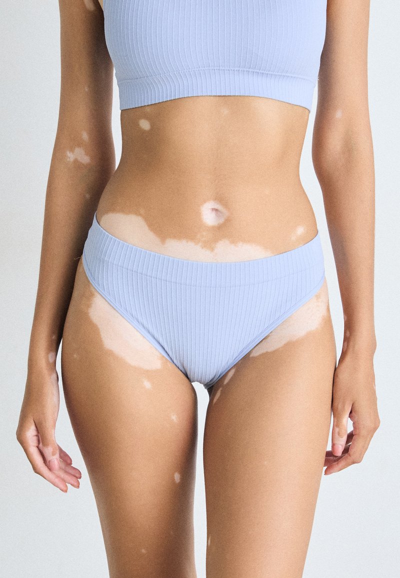 Ljusblå randig bikiniuppsättning med crop top och högmidjade trosor. Mjuk textur, enkel design, minimalistisk stil.