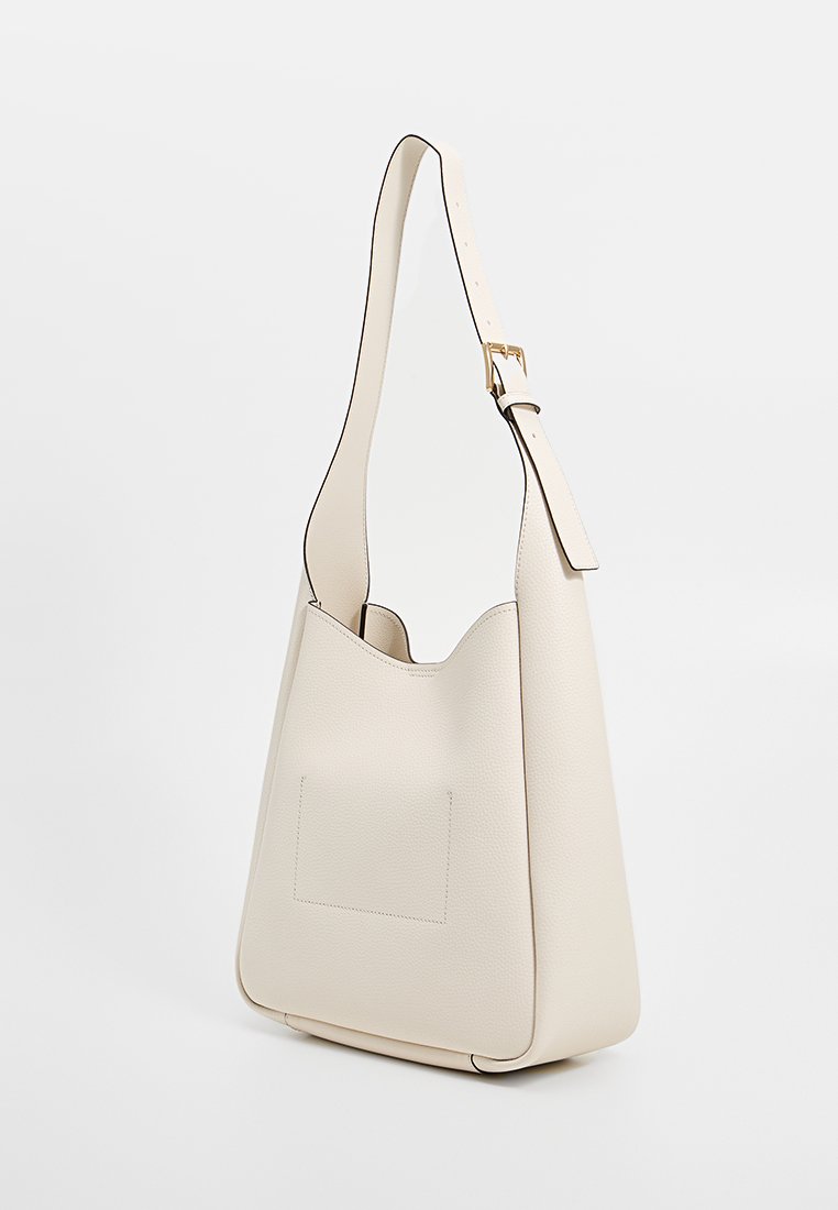 Borsa a spalla in pelle beige con una superficie morbida e testurizzata, apertura superiore e tasca piatta sul davanti. Tracolla regolabile con hardware dorato.
