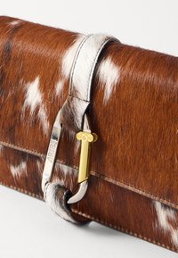 Brun og hvid plettet clutch i pels med metallisk accent, der har et elegant design og en struktureret overflade.