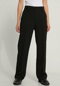 Black tailored trousers with a straight cut, flat front, and belt loops, made from smooth fabric. Features side pockets and a clean finish.