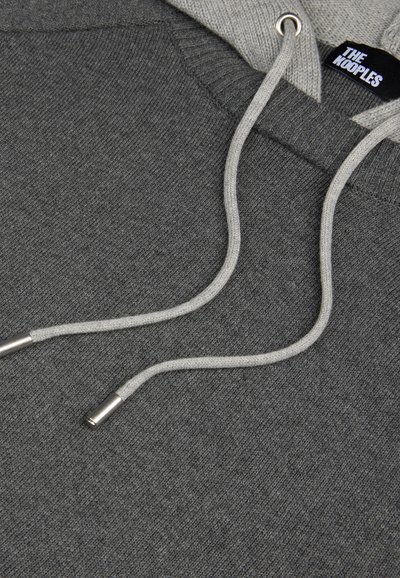 Hoodie grigia con una texture morbida, dotata di un laccio grigio chiaro e punte metalliche argentate. L'etichetta riporta "THE KOOPLES."