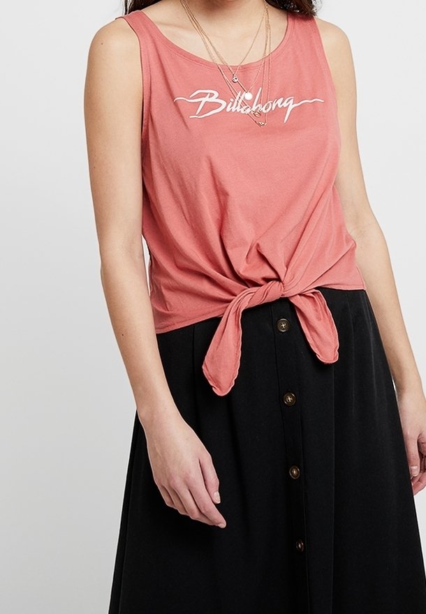 Koralfarvet tanktop med knude foran, med hvid "Billabong"-logo. Båret med en sort nederdel med knapper ned foran.