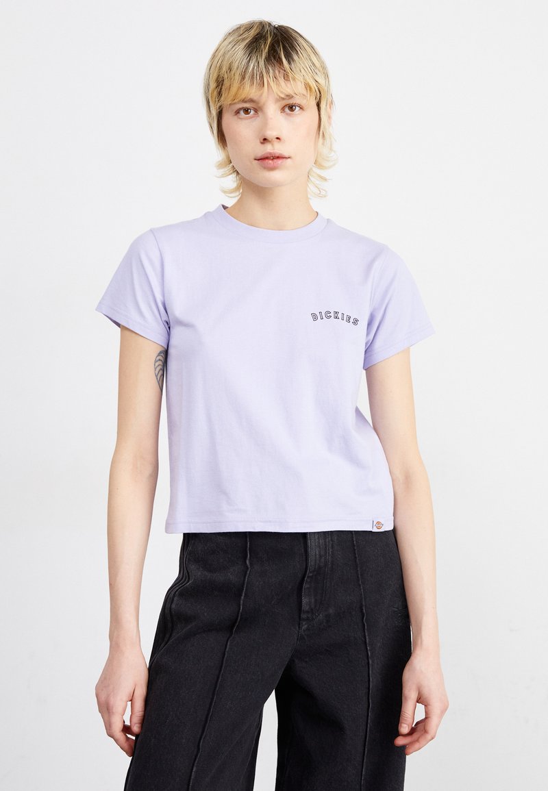 T-shirt in cotone lilla chiaro con colletto rotondo, maniche corte e un piccolo logo nero sul lato sinistro del petto. Design cropped con una vestibilità rilassata.
