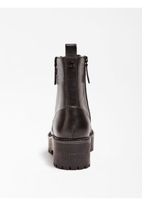 Stivaletti neri in pelle con punta rotonda, chiusura con zip laterale, tacco impilato e logo "GUESS" in rilievo sul retro.