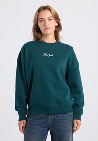 Sudadera de algodón verde con cuello redondo, hombros caídos y puños de canalé. Texto bordado "New York" en blanco en el pecho.