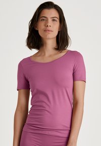 Short-sleeve pink t-shirt made of soft, stretchy fabric with a scooped neckline and fitted cut, suitable for casual wear.