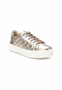 Zapatillas metálicas de bronce con textura acolchada, parte frontal con cordones y suela de goma blanca. Presentan un branding sutil en el lateral.