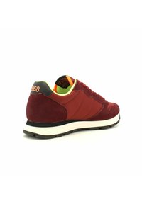 Scarpe sportive di colore bordeaux con una combinazione di materiali in suede e tessuto. Presentano un tallone nero, una fodera verde brillante e una suola in gomma bianca spessa.
