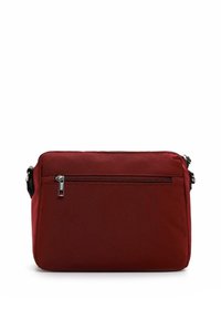 Červená látková crossbody taška obdélníkového tvaru, s přední kapsou na zip a černými kovovými detaily. Matný povrch, kompaktní design.