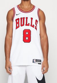 Maglia da basket bianca con accenti rossi. Presenta la scritta "BULLS" e il numero "8" in grassetto di colore rosso. Logo Nike visibile sulla spalla.
