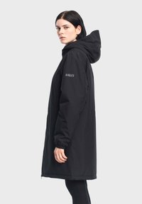 Parka nera lunga con cappuccio, dotata di polsini elasticizzati e chiusura con zip sul davanti. Logo Aigle stampato sulla manica sinistra. Texture liscia.