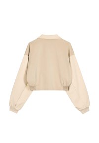 Beige Jacke mit Kragen, übergroßen Ärmeln und gerafften Bündchen. Glatte Textur mit minimalistischem Design.