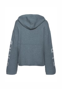 Felpa con cappuccio grigio mélange, tagliata. Presenta spalle scese e dettagli testuali bianchi sulle maniche. Finitura morbida e testurizzata.