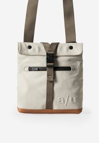 Grijze stoffen crossbodytas met een bruine onderkant, voorzien van een voorvak met rits en een verstelbare schouderriem. Logo gegraveerd aan de zijkant.