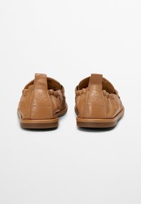 Brown leren instappers met een zachte, gestructureerde oppervlakte, afgeronde vorm en decoratieve stiksels. Bevat een kleine lus bij de hak.