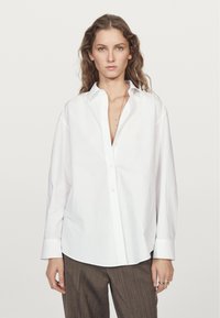 Camicia bianca con bottoni, dal fit rilassato, maniche lunghe, colletto a punta e orlo dritto, realizzata in morbido tessuto di cotone.