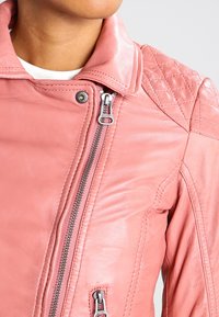 Roze leren motorjack met een aansluitend ontwerp, voorzien van gewatteerde schouderaccenten, zilverkleurige details en een ritssluiting aan de voorkant.