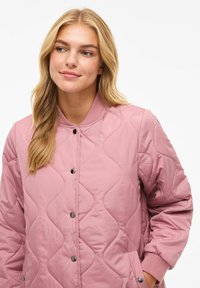 Roza prešita jakna z rebrastim ovratnikom, pritiskači in stranskimi žepi; ima gladko teksturo in vzorec valovitega šivanja.