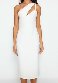 Robe midi blanche avec une silhouette ajustée, comportant un décolleté asymétrique, une bretelle unique à l'épaule, et une découpe incurvée sur la poitrine.