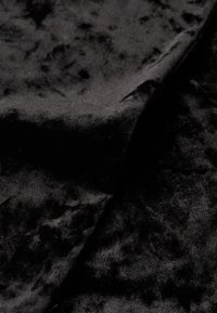 Czarna aksamitna tkanina o miękkiej fakturze, z delikatnym połyskiem i niewielkimi różnicami w głębokości. Złożona, aby pokazać gładkie krawędzie i powierzchnię.