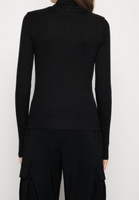 Schwarzes Rollkragenoberteil mit langen Ärmeln, aus gerippter Stoffqualität. Fitted-Design mit glatter Textur, ohne sichtbare Muster oder Verzierungen.