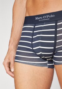 Marine gestreifte Boxershorts mit weißen horizontalen Linien, versehen mit einem markenbezogenen Bund, aus weichem Material und in körpernaher Passform.