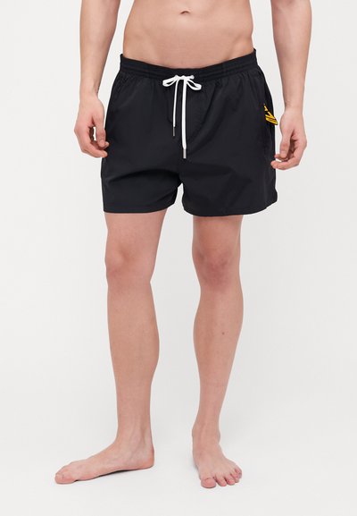Schwarze Badeshorts mit elastischem Bund und weißem Kordelzug. Zu den Merkmalen gehören Seitentaschen und ein gelbes Akzentdetail an der linken Oberschenkel.