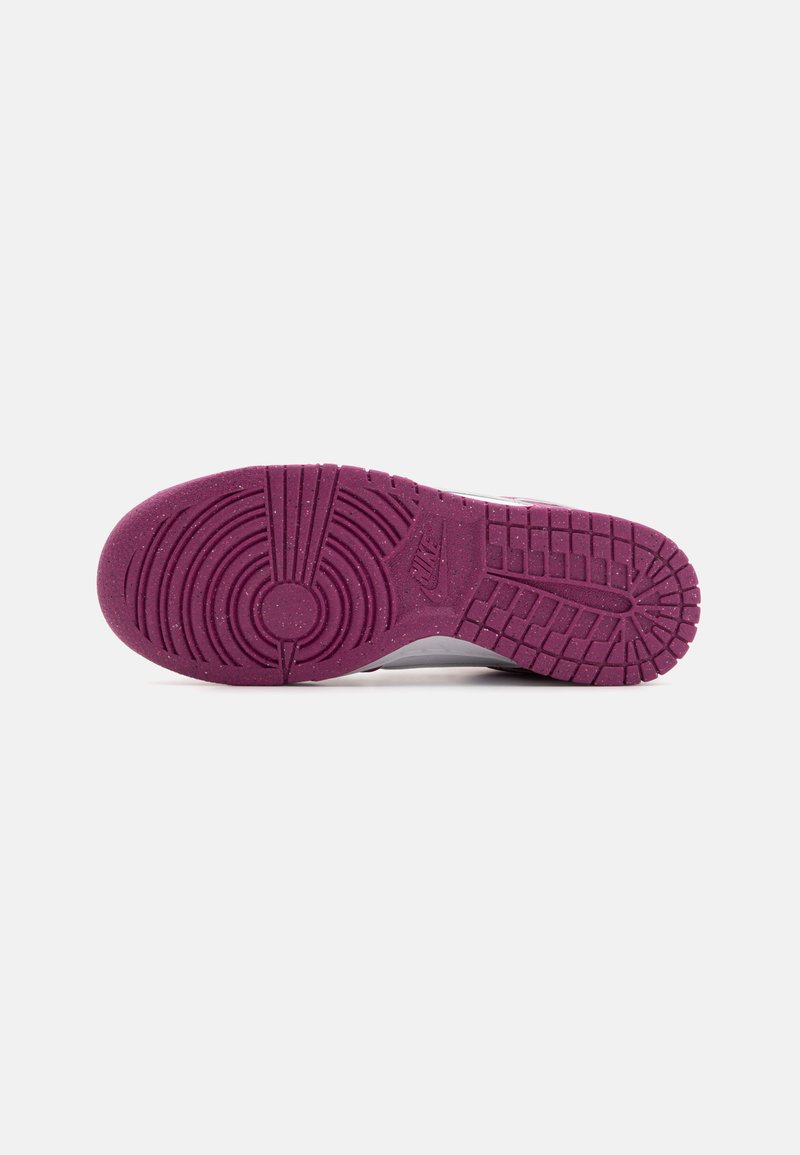 Semelle de chaussure Nike avec une base en caoutchouc violet présentant des motifs de bande de roulement circulaires et linéaires pour l'adhérence. Comprend des accents texturés pour une meilleure prise.